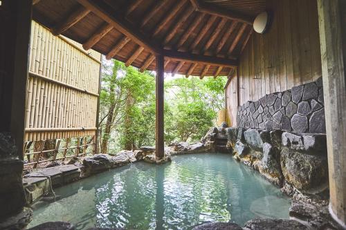 a swimming pool in a house with a stone wall at Shiki Resort Forest Hakone in Hakone