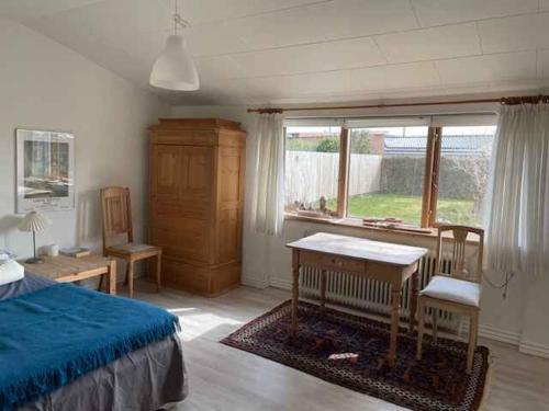 een slaapkamer met een bed, een bureau en een raam bij Charming Townhouse With Plenty Of Space in Thyborøn