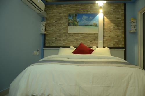 a bedroom with a large white bed with red pillows at Isle inn {Fuvahmulah) in Fuvahmulah