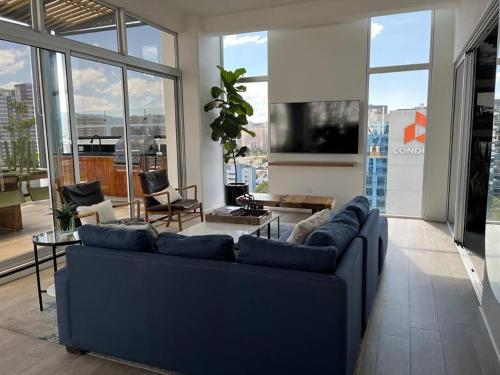 a living room with a blue couch in a room with windows at APARTAMENTO CON TERRAZA CERCA DEL AEROPUERTO in Guatemala