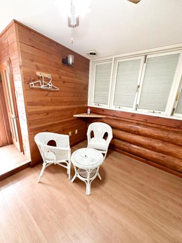 a room with two chairs and a table and two windows at ホテル亀岡 in Minamijō