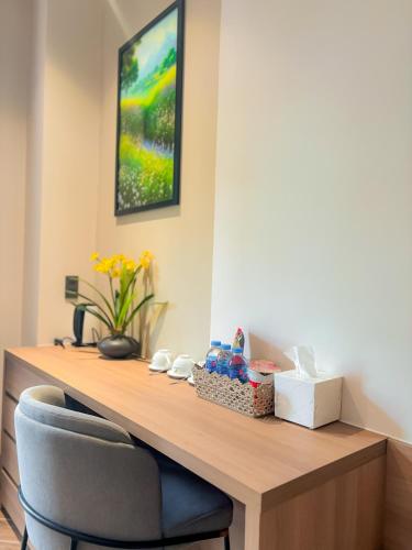 a desk in a room with a chair and flowers at KHÁCH SẠN THƯ LÊ LUXURY in Cao Lãnh