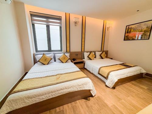 two beds in a room with a window at KHÁCH SẠN THƯ LÊ LUXURY in Cao Lãnh