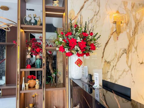un vase rempli de fleurs rouges sur une étagère dans l'établissement KHÁCH SẠN THƯ LÊ LUXURY, à Cao Lãnh