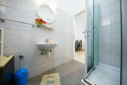 a bathroom with a sink and a shower and a mirror at Seafront apartment Jurkovica in Komiža