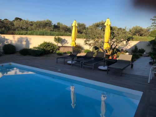 - une piscine avec 2 parasols et chaises jaunes dans l'établissement Les Lavandins-Gite Vincent, à Saint-Rémy-de-Provence