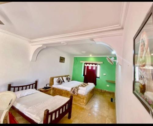 Habitación con 2 camas y pared verde. en Hotel Dream Night Jaisalmer en Jaisalmer