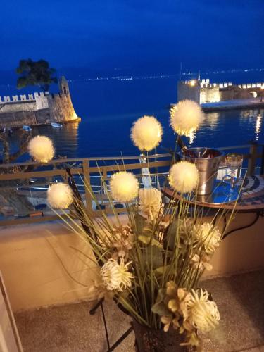a vase filled with white flowers on a balcony with the ocean at Casa da Sogno Elegant Studio in Nafpaktos