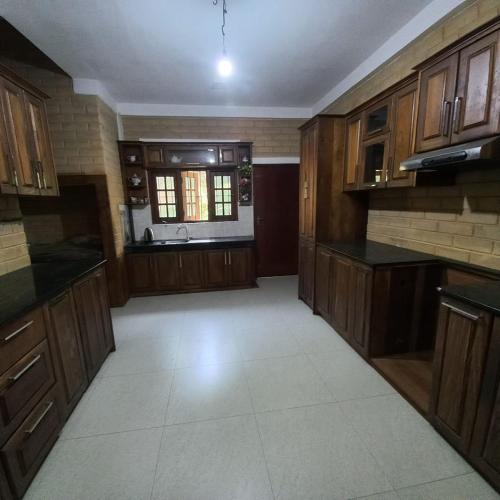 a large kitchen with wooden cabinets and a window at senik villa in Kalutara