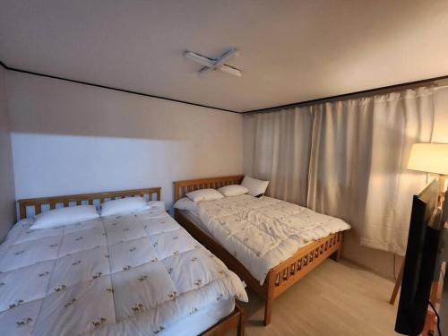 a bedroom with two beds and a ceiling fan at Yeongdeungpo Windsor in Seoul