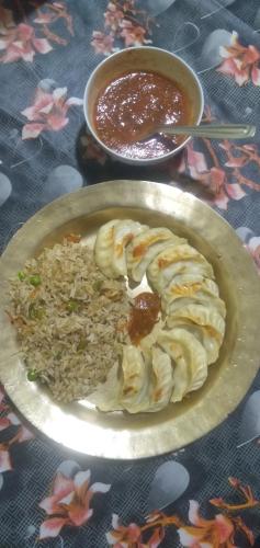 a plate of food with rice and a bowl of sauce at BLUE DUKE HOMESTAY in Ravangla