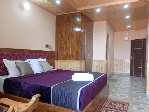 um quarto com uma cama grande e um cobertor roxo em Atithi Homestay & Bhojnalya, Chail em Chail
