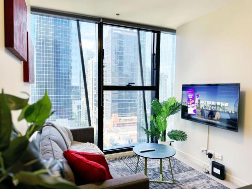 a living room with a couch and a table and a large window at Collins Serviced Apartments in Melbourne