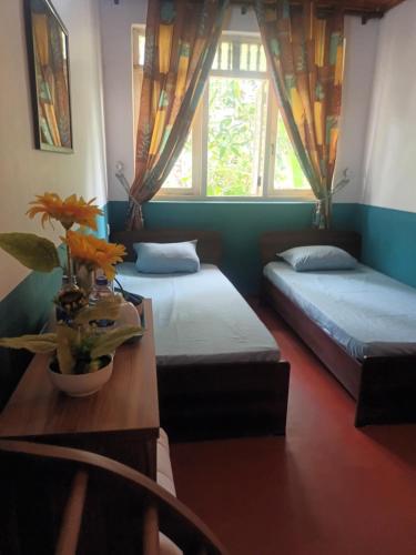 a room with two beds and a table with flowers at Lovely FLowers in Mount Lavinia in Mount Lavinia