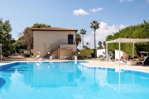 a swimming pool in front of a villa at Hotel Aria di Mare in Marina di Ragusa