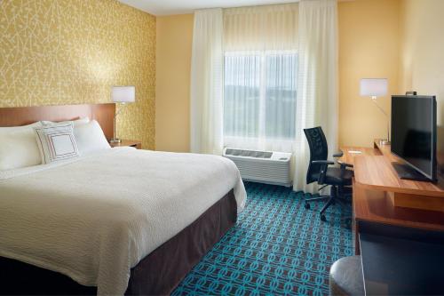 a hotel room with a bed and a desk and a television at Fairfield Inn & Suites by Marriott Hendersonville Flat Rock in Flat Rock