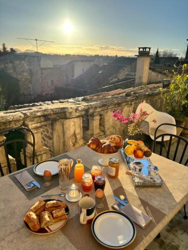 a table with a breakfast of bread and orange juice at La vie de chateau in Grignan