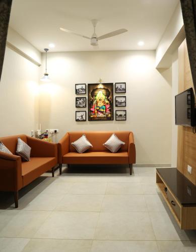 a waiting room with two orange couches and a tv at Sumadhu Homes -Family Homestay in Kolhapur