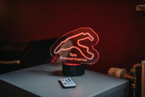 a red neon sign on a table next to a remote control at Le refuge de Kila in Waimes