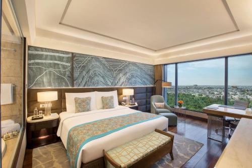 a bedroom with a large bed and a large window at The Leela Ambience Convention Hotel Delhi in New Delhi