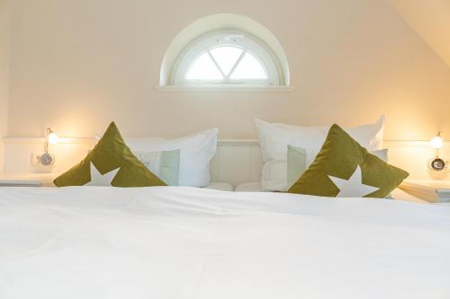 Cama blanca con almohadas verdes y ventana en Senmare, en Munkmarsch
