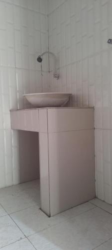 a white sink in a white tiled bathroom at D'La CoCo Villa in Bangli