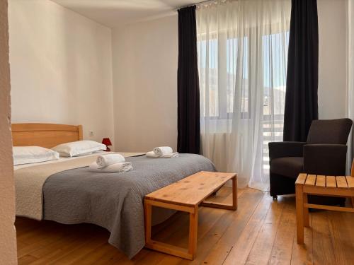 a bedroom with a bed and a chair and a window at Beko’s garden Inn in Mestia