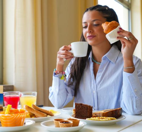a woman sitting at a table drinking a cup of coffee at Hotel Regent in Pescara