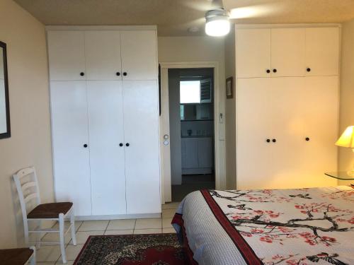a bedroom with white cabinets and a bed and a chair at phoenixonking in Buderim
