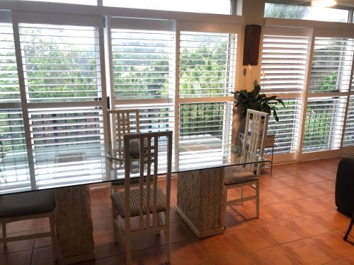 a dining room with a glass table and some windows at phoenixonking in Buderim