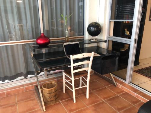 a black desk with two chairs and a red vase at phoenixonking in Buderim