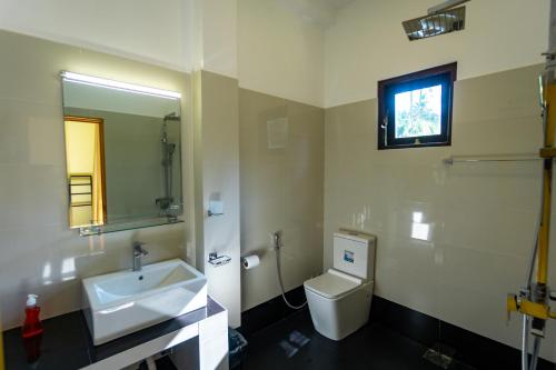 a bathroom with a sink and a toilet and a mirror at Charlie Breeze in Ahangama