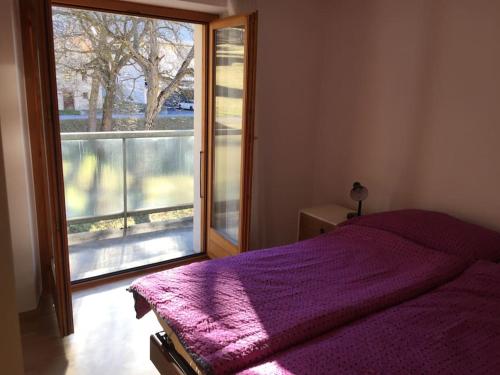 a bedroom with a purple bed and a large window at Appartement Casa Rancurina in Olivone