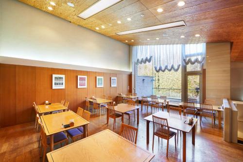 une salle à manger avec des tables et des chaises en bois dans l'établissement Shiki Resort Ventvert Karuizawa, à Karuizawa