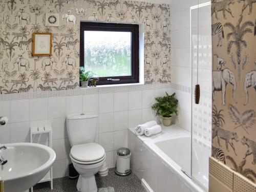 a bathroom with a toilet and a tub and a sink at Angerton Cottage in Kirklinton