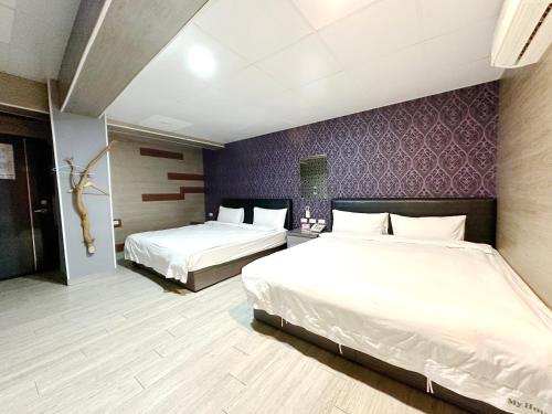 a bedroom with two beds and a purple wall at My House Hotel in Luodong