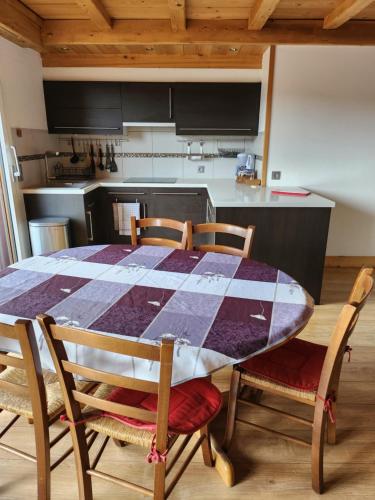 een keuken met een tafel met vier stoelen en een keuken bij Les Balcons du Mont-Blanc : Appartement centre village in Cordon