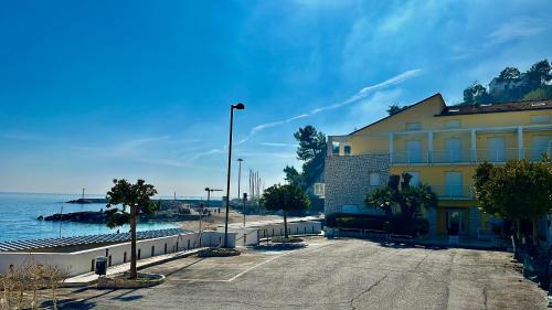 a building with a parking lot next to the water at N276 - Numana, bilocale fronte Spiaggiola con piscina in Numana