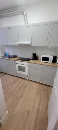 a kitchen with white cabinets and a counter with a microwave at Au pied du théâtre in Verviers