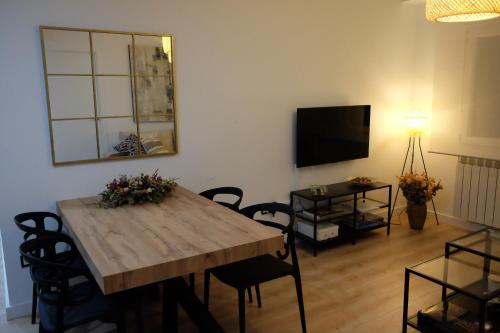 ein Wohnzimmer mit einem Holztisch und einem TV in der Unterkunft Capricho Lostal in Saragossa