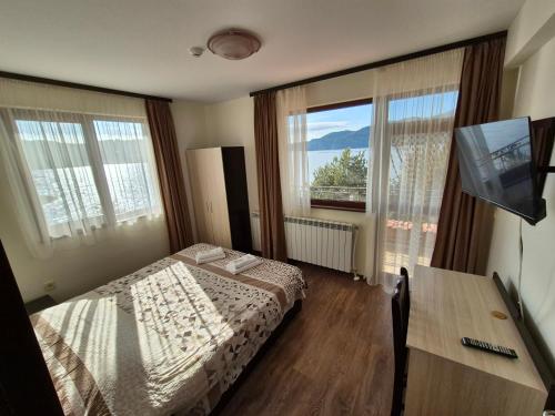 a bedroom with a bed and a desk with a television at Divna Guest House in Dospat