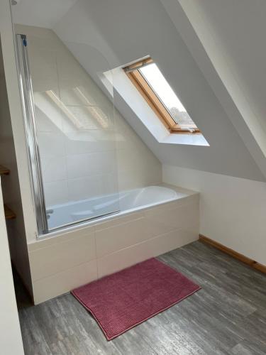 La salle de bains est pourvue d'une baignoire, d'une fenêtre et d'un tapis. dans l'établissement Maison centre-ville avec extérieurs, à Lannion