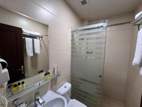 a bathroom with a toilet and a glass shower at Hotel Byond Tashkent in Tashkent
