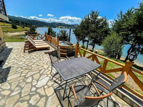 a patio with a table and chairs and a lake at Divna Guest House in Dospat