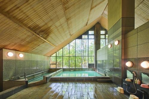 a large bathroom with a swimming pool with a large window at Shiki Resort Belufore Nasu in Nasu