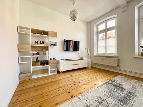 Dieses weiße Zimmer verfügt über einen Schreibtisch und einen TV. in der Unterkunft FeWo Meeres Luft in Wismar