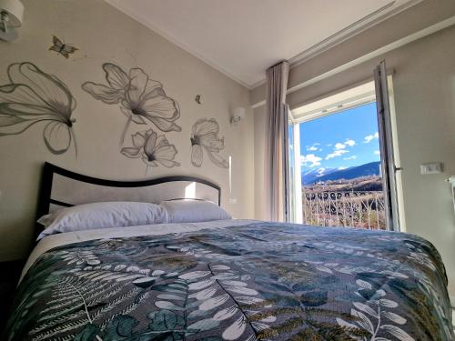 1 dormitorio con 1 cama y una ventana con flores en la pared en Il Filo Rosso en LʼAquila