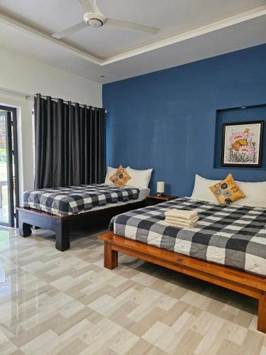 a bedroom with two beds and a blue wall at Catsen Bungalows & Pool Phan Thiet in Phan Thiet