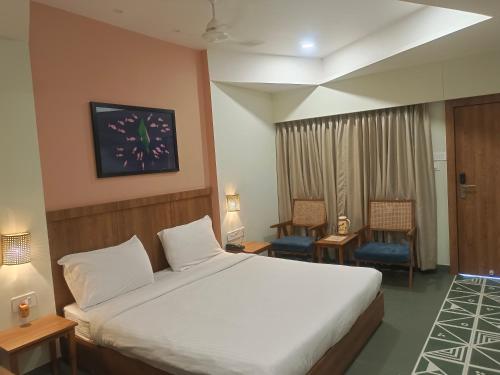 a hotel room with a bed and two chairs at Hotel Ashray in Ujjain
