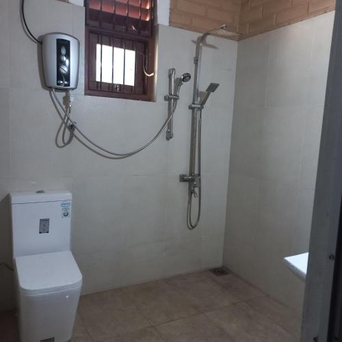 a bathroom with a shower and a toilet and a window at senik villa in Kalutara